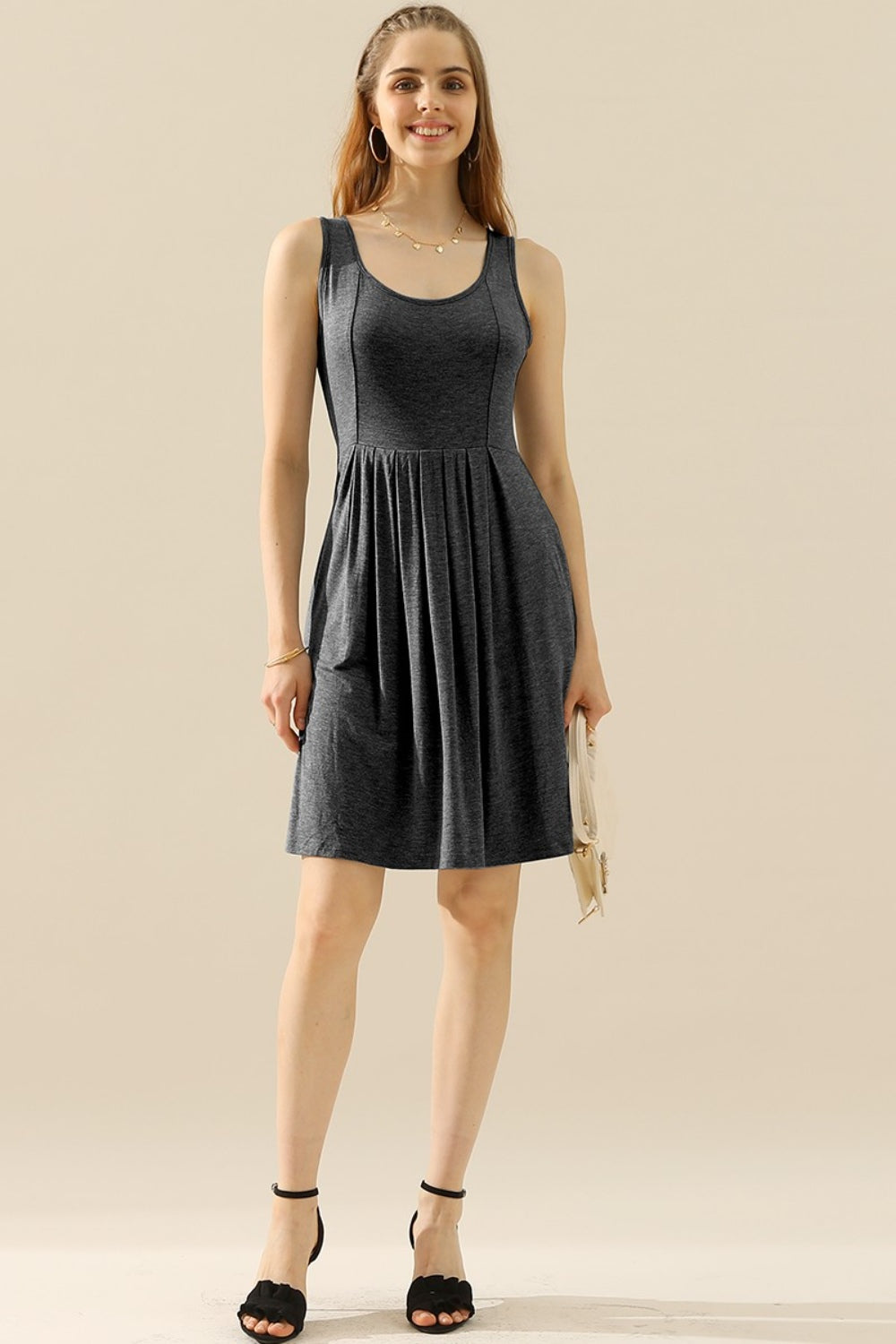 Woman wearing a sleeveless round neck ruched dress with pockets, made of stretchy polyester and spandex, in a basic style.