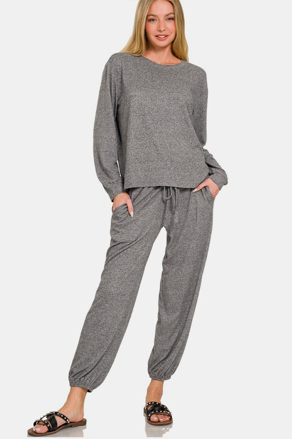 Woman wearing a chic round neck t-shirt and joggers set in soft gray fabric, featuring a drawstring waist and pockets for casual comfort.