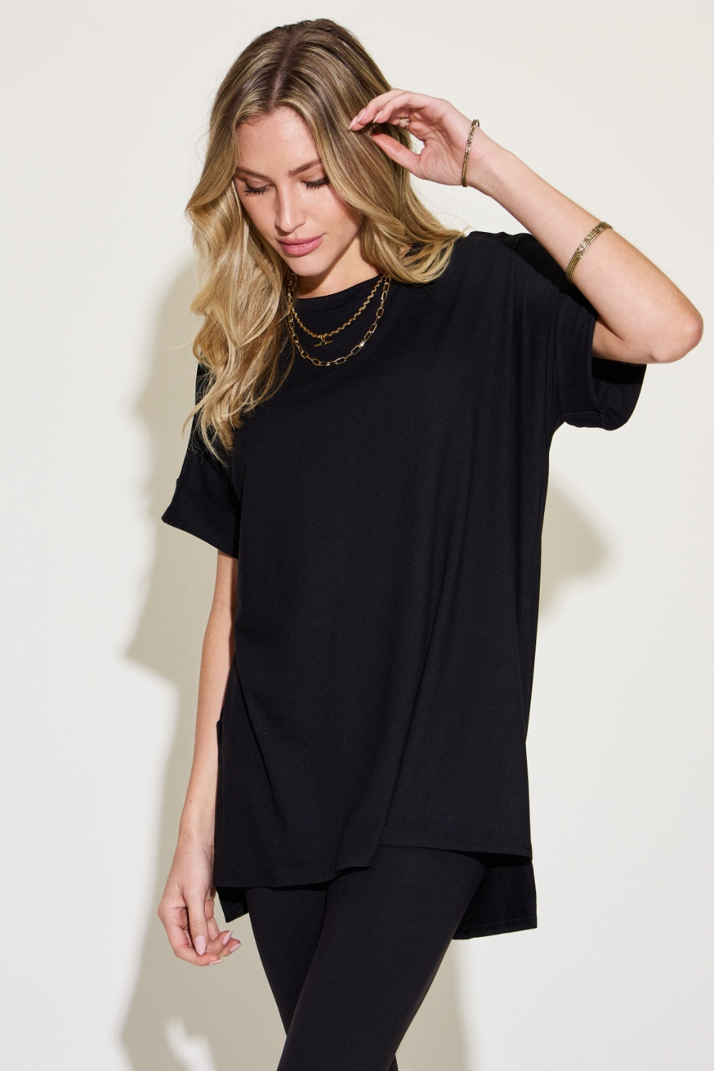 Woman wearing a black short sleeve slit t-shirt and leggings lounge set, featuring a chic and comfortable loungewear style.