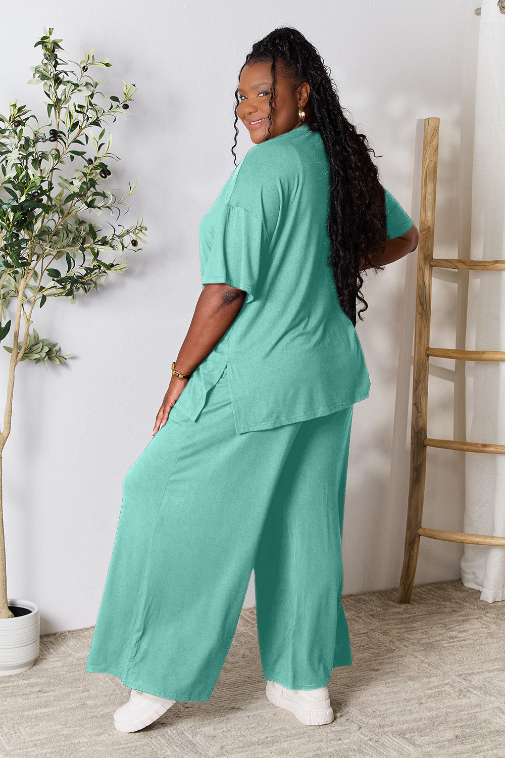 Woman modeling teal double take round neck slit top and pants set, showing back detail and comfortable fit.