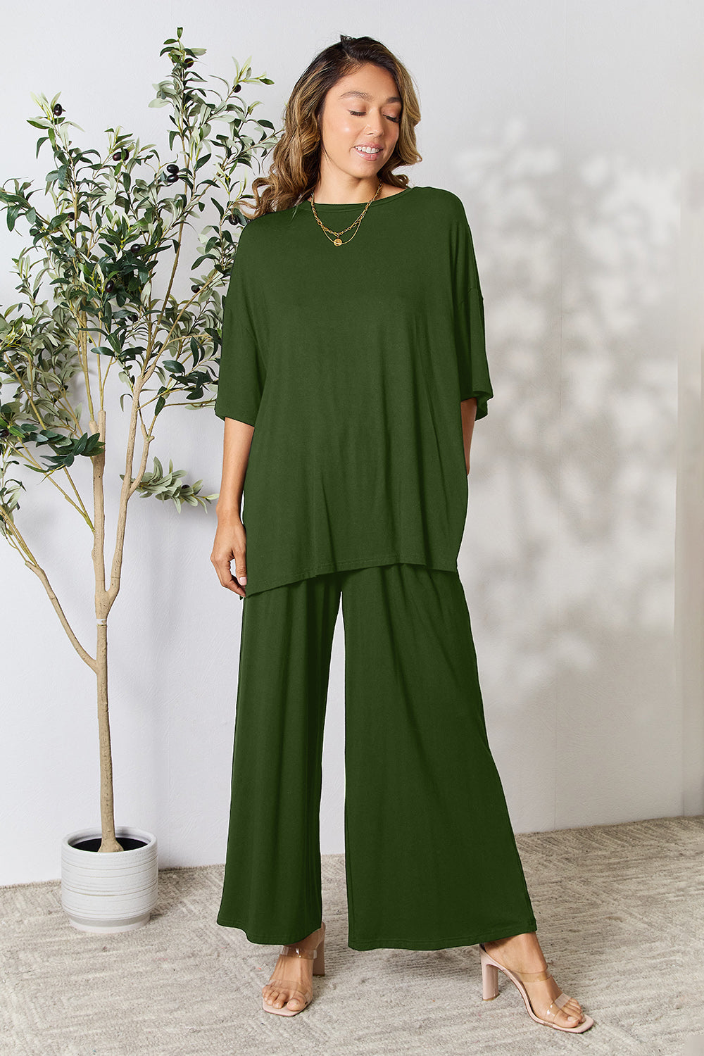 Woman wearing green round neck slit top and pants set with comfortable fit, standing in stylish indoor setting.