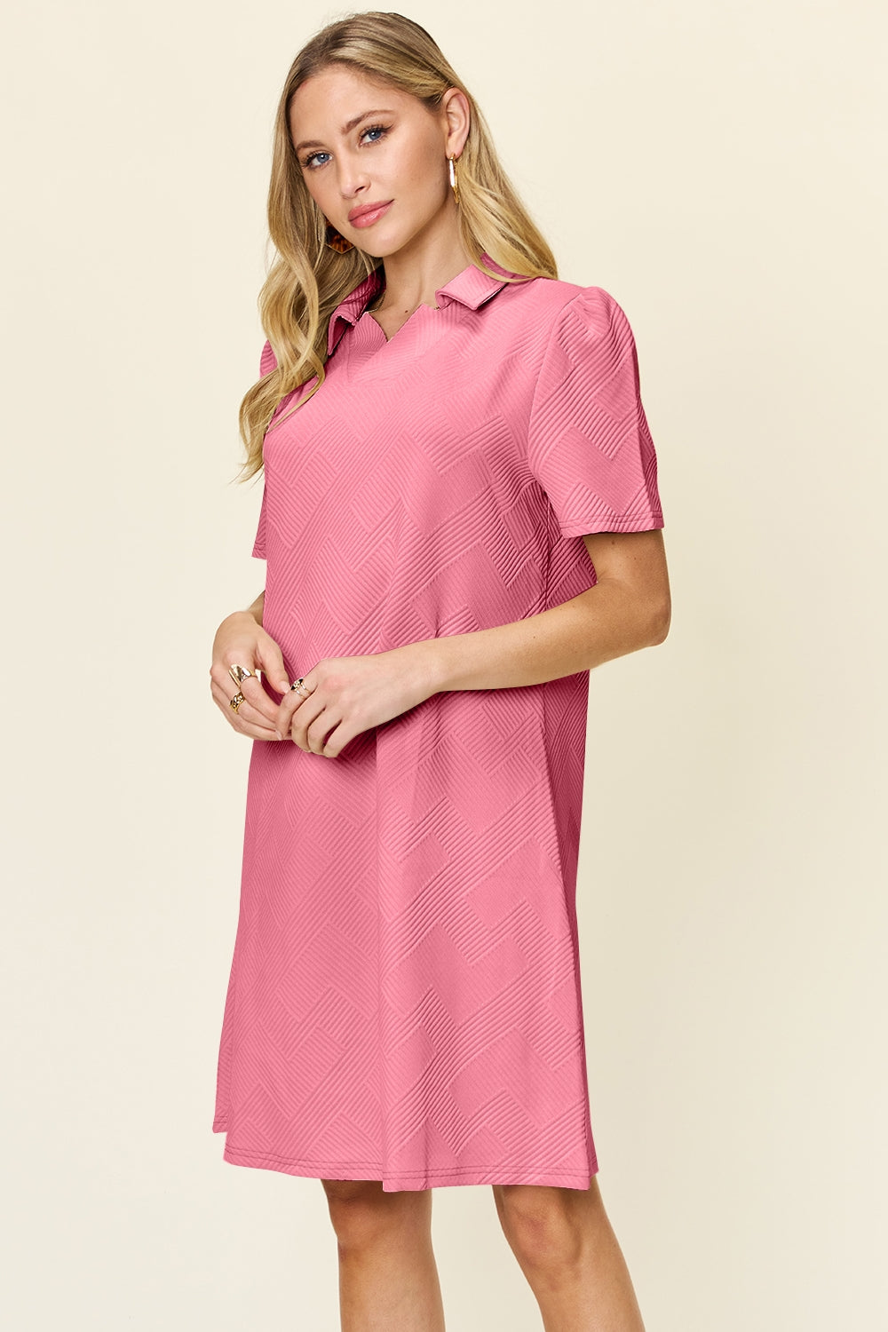 Woman wearing a pink texture collared neck short sleeve dress, showcasing a casual, slightly stretchy style made from polyester and spandex.