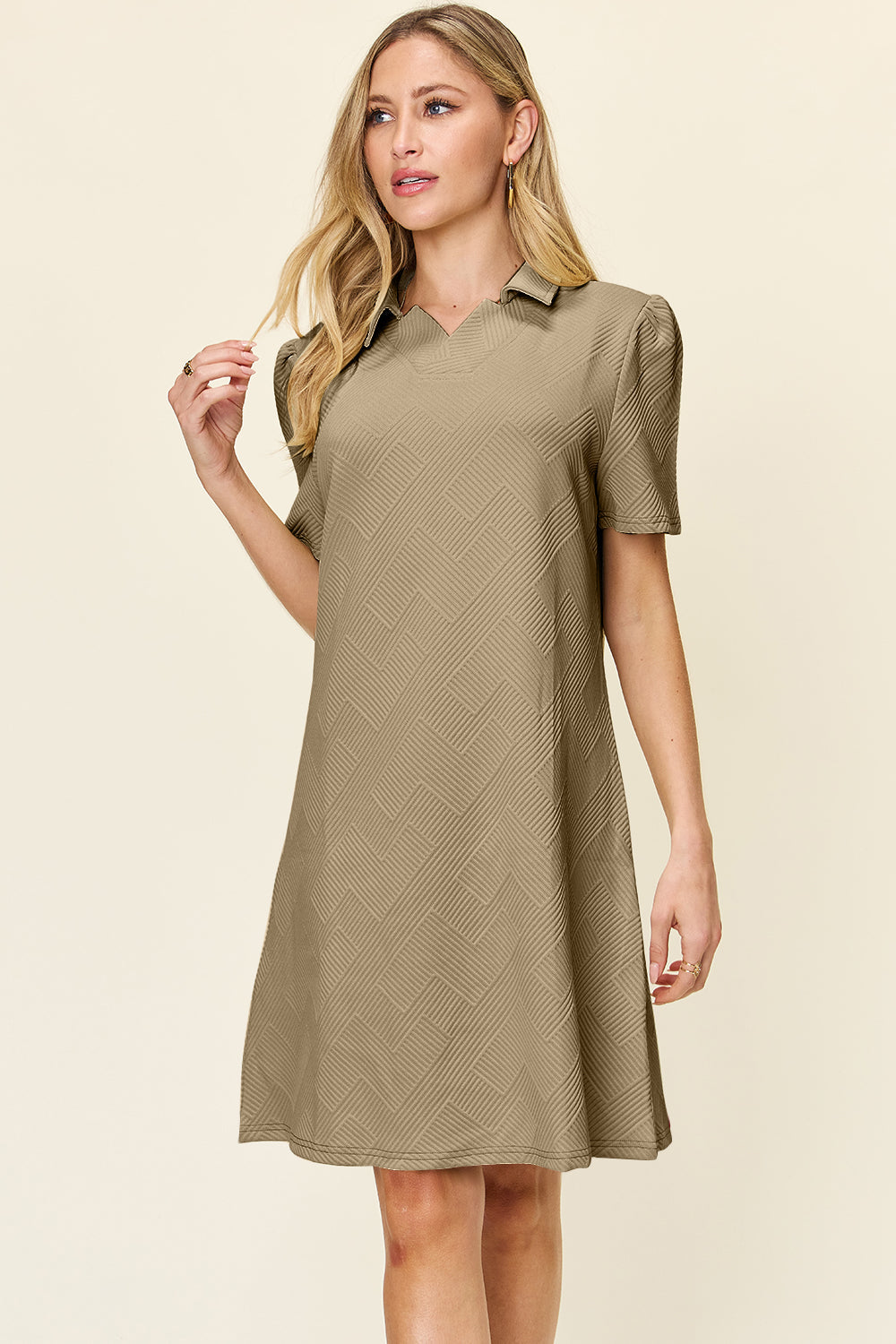 Woman wearing a texture collared neck short sleeve dress, beige color, slightly stretchy fabric, made of polyester and spandex.