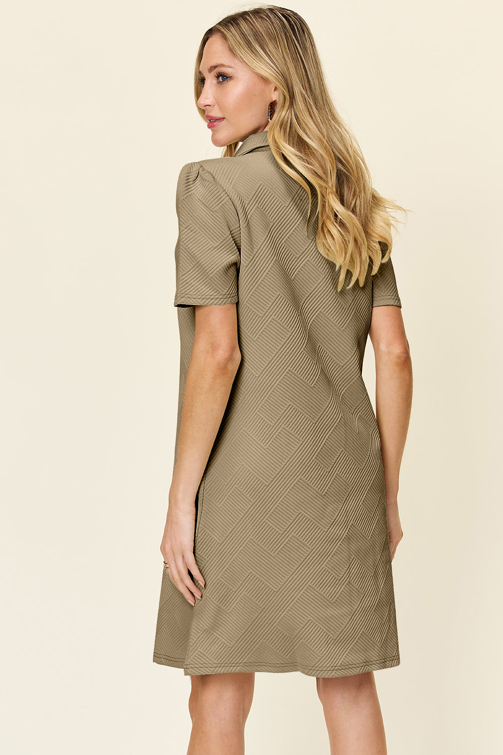 Woman wearing a texture collared neck short sleeve dress with a slightly stretchy fit, made from polyester and spandex.