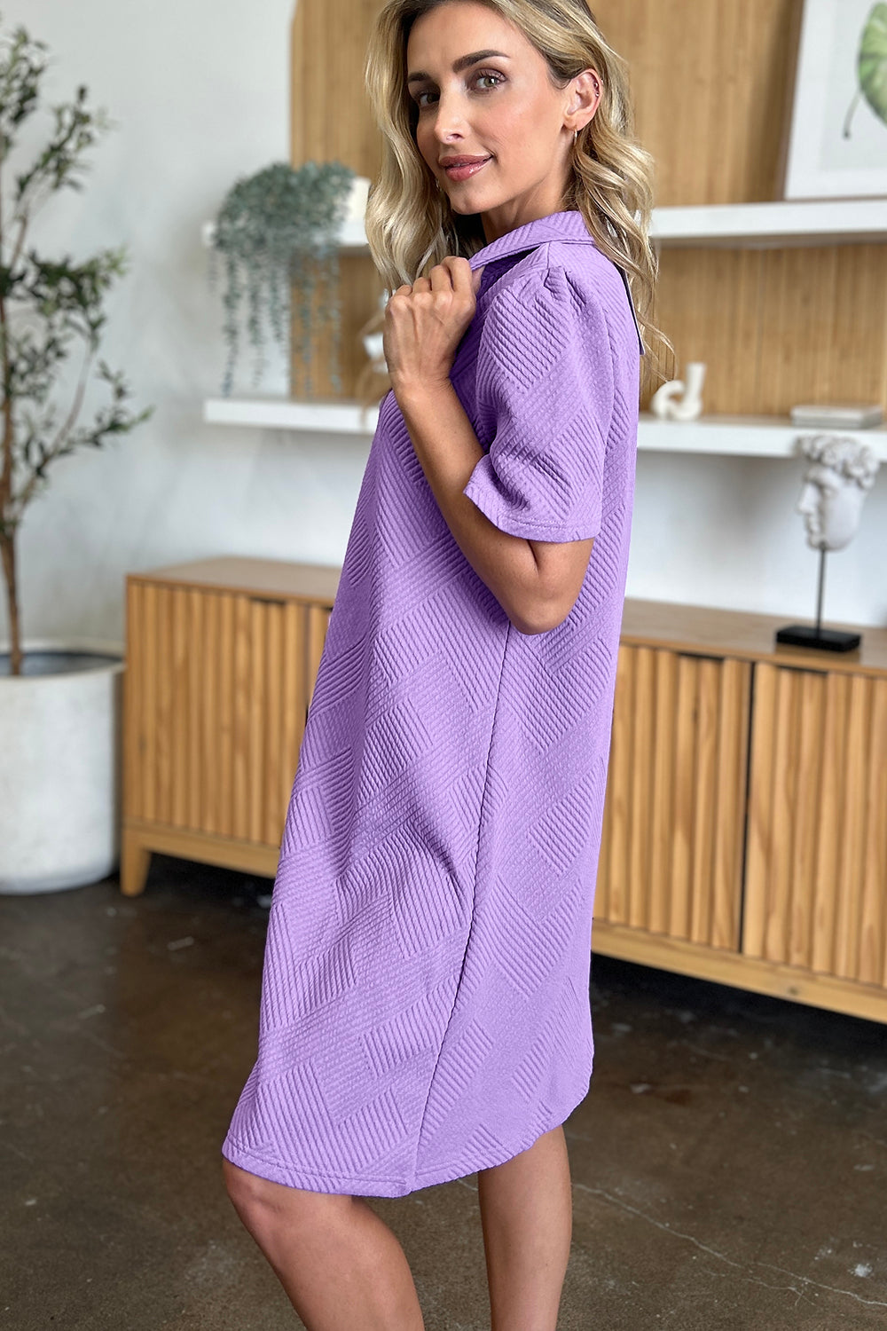 Woman wearing a purple texture collared neck short sleeve dress, showcasing the basic style in a modern indoor setting.