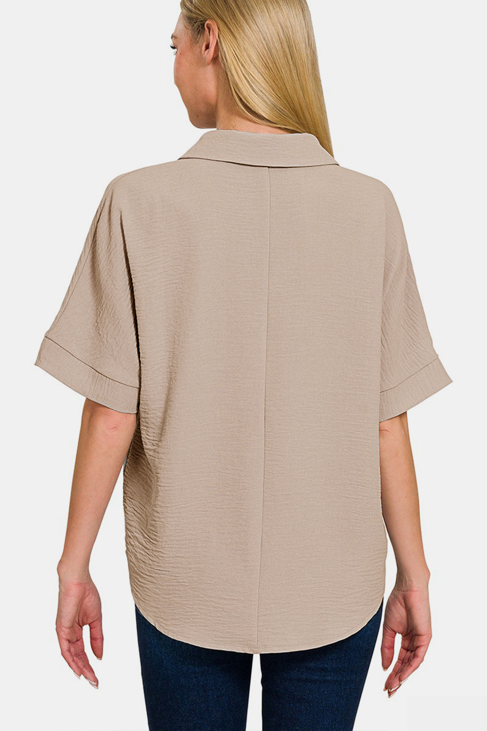 Woman wearing beige texture collared neck short sleeve top, showing back detail and flattering fit, paired with jeans.