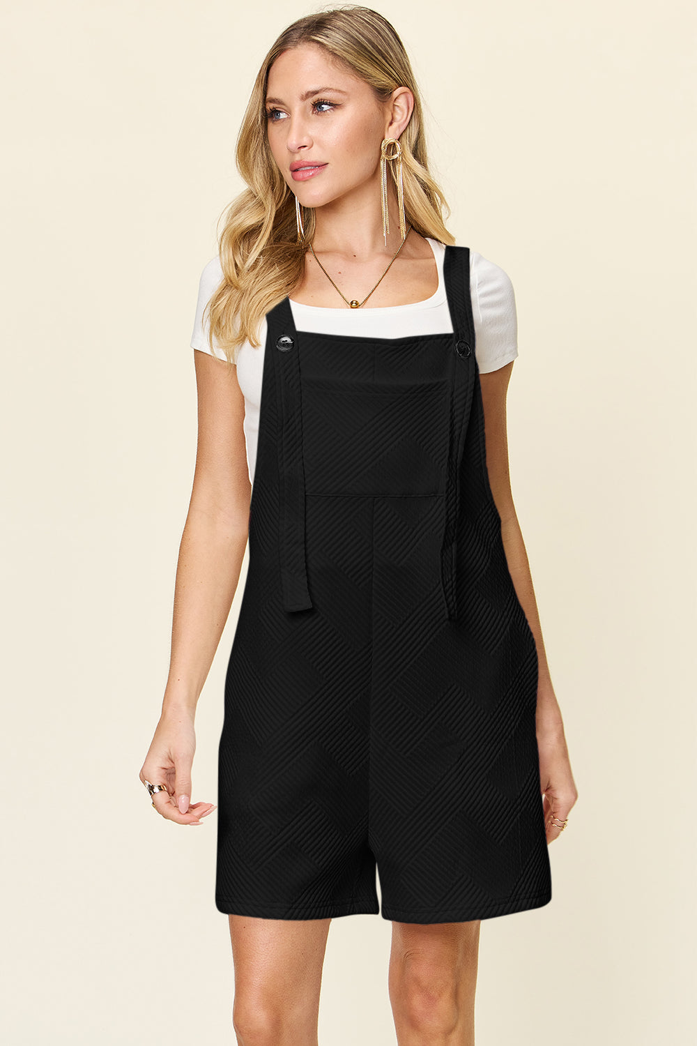 Woman wearing black texture sleeveless romper with a white shirt underneath, showcasing basic style and full size fit.