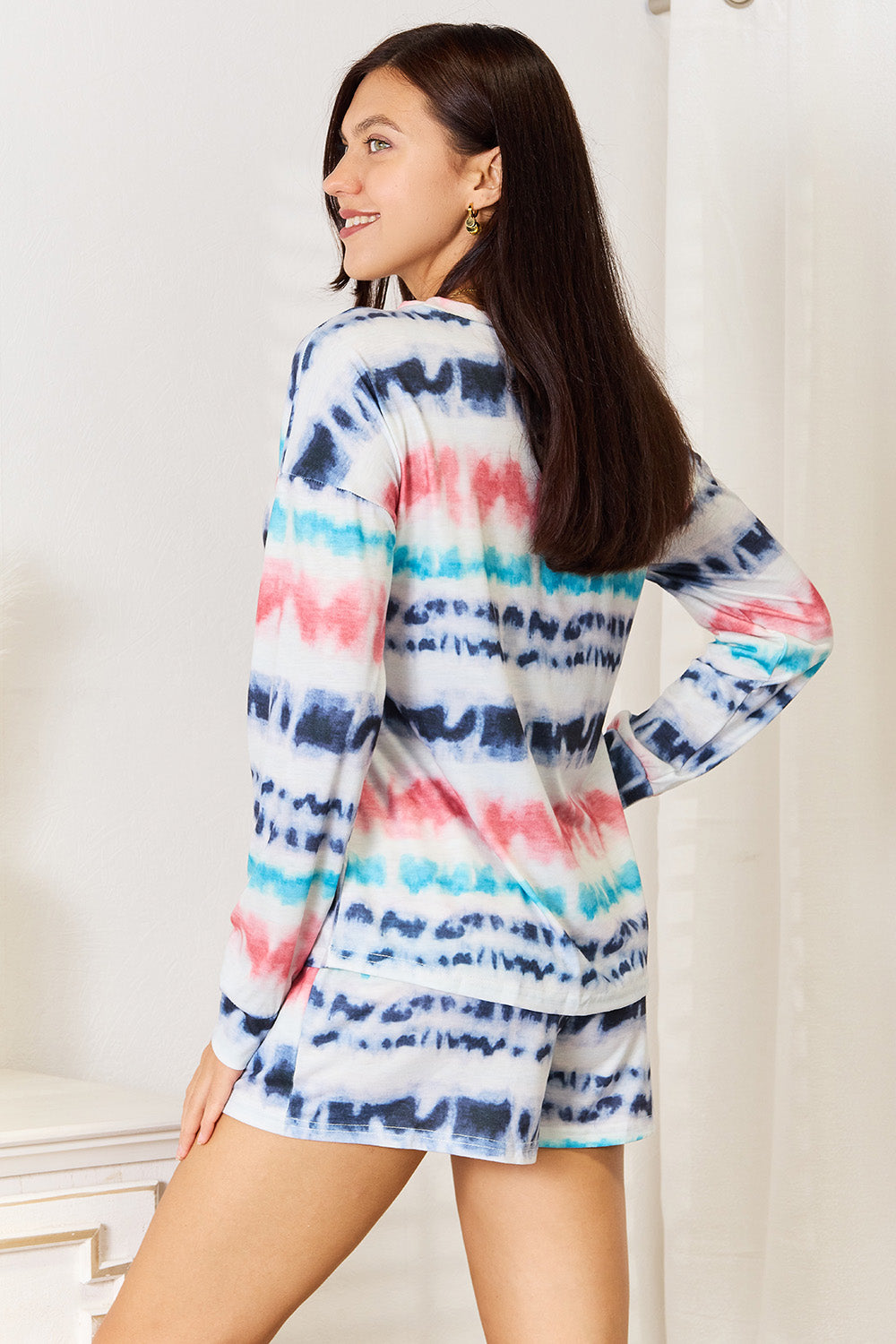 Woman wearing a trendy tie-dye dropped shoulder lounge set, featuring a relaxed fit and vibrant colors, perfect for comfort and style.