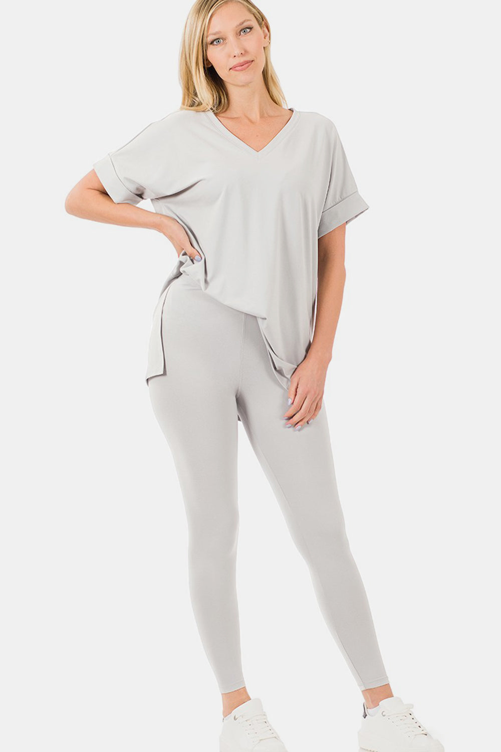 Woman wearing a chic V-neck rolled short sleeve T-shirt and leggings lounge set in gray, styled with white sneakers for casual comfort.