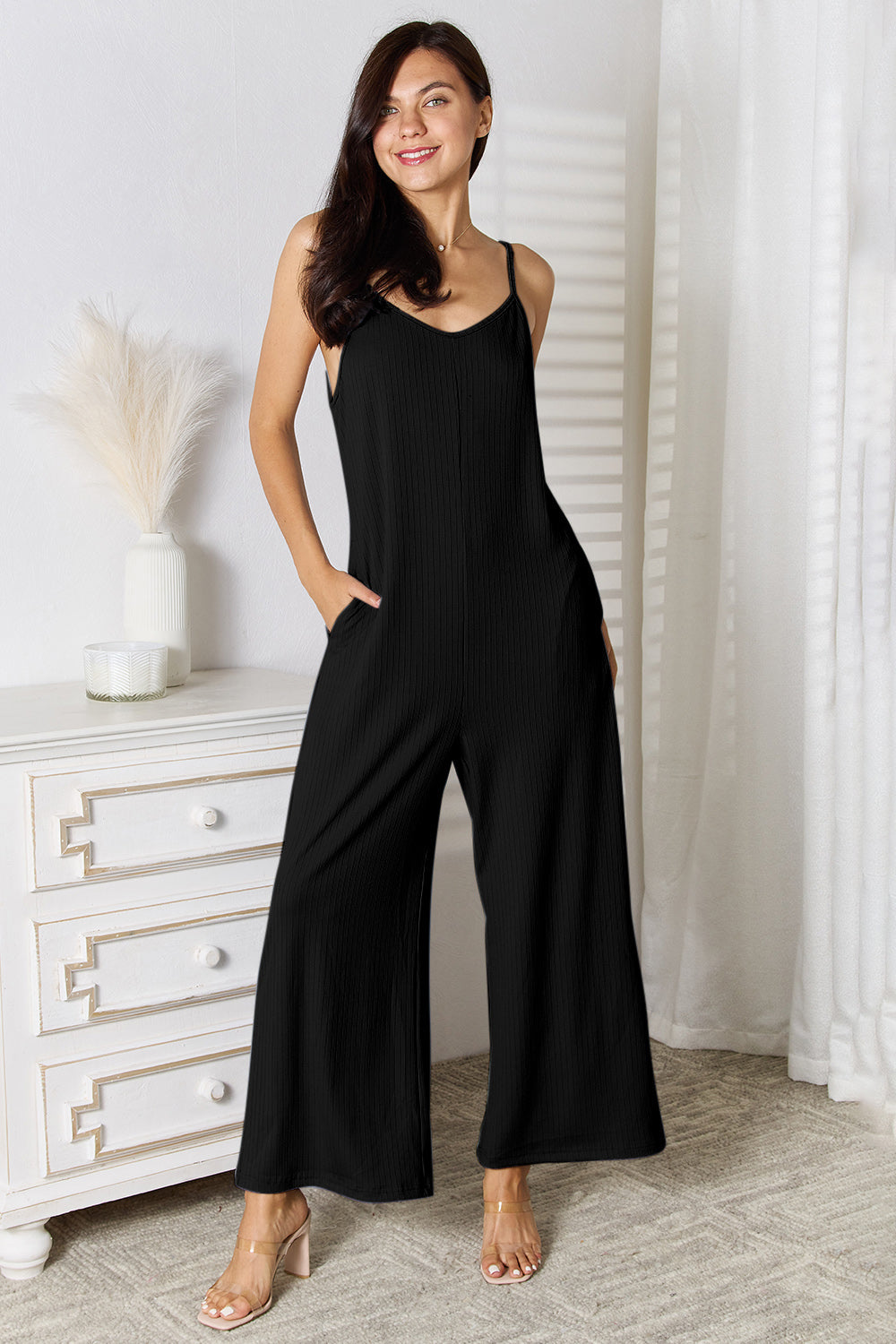 Woman wearing a chic black spaghetti strap V-neck jumpsuit with a flattering fit, perfect for a night out or special occasion.