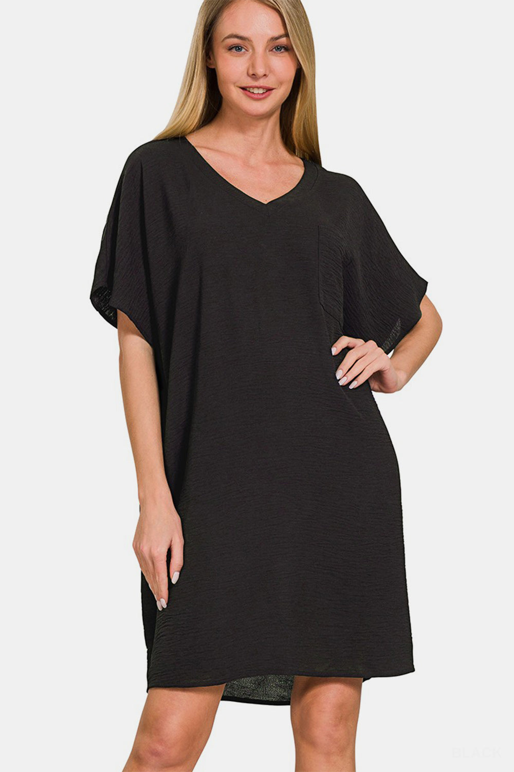 Woman wearing black V-neck tee dress with pockets, showcasing classic silhouette and chic style.