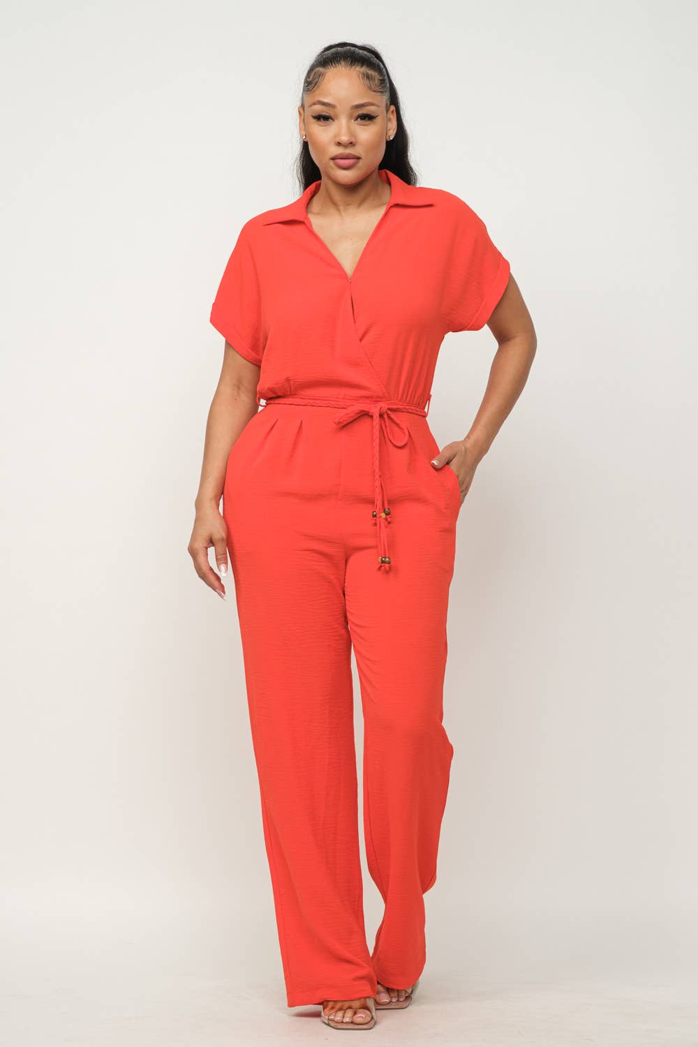 Red open front jumpsuit with waist tie, inside button detail, collared short sleeves, and wide-leg pants.