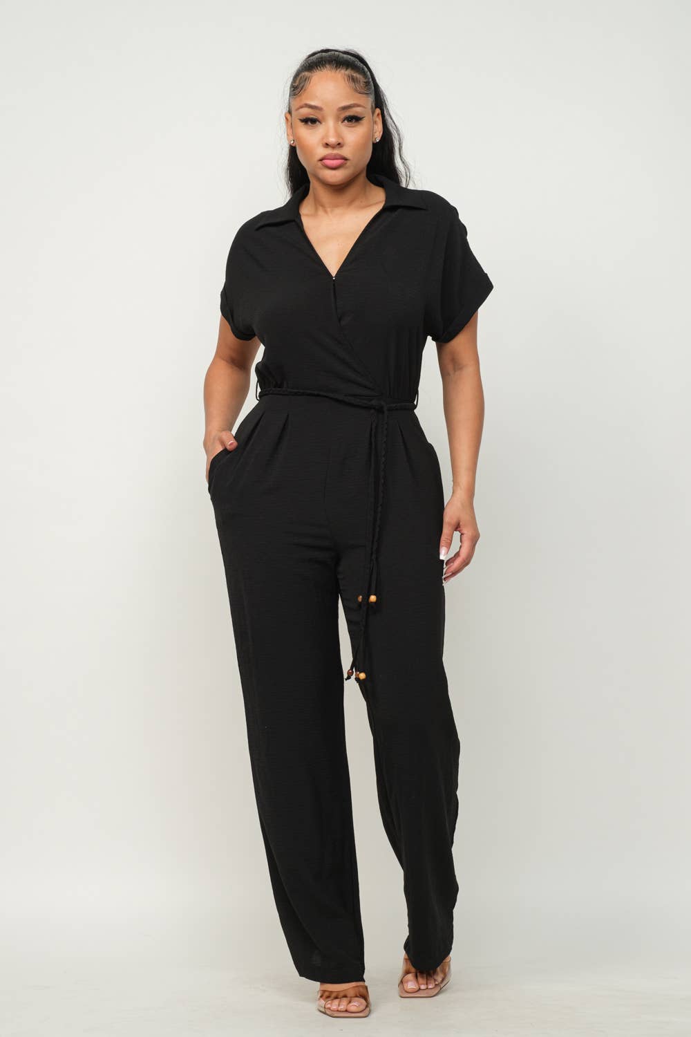 Black open front jumpsuit with elastic waist tie, short sleeves, and wide leg pants, featuring side pockets and collar detail.