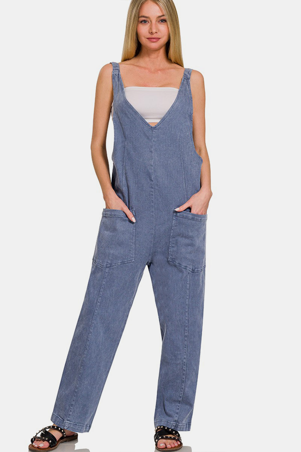 Woman wearing a chic pocketed wide strap jumpsuit in denim, featuring a flowy fit and functional pockets, perfect for versatile styling.