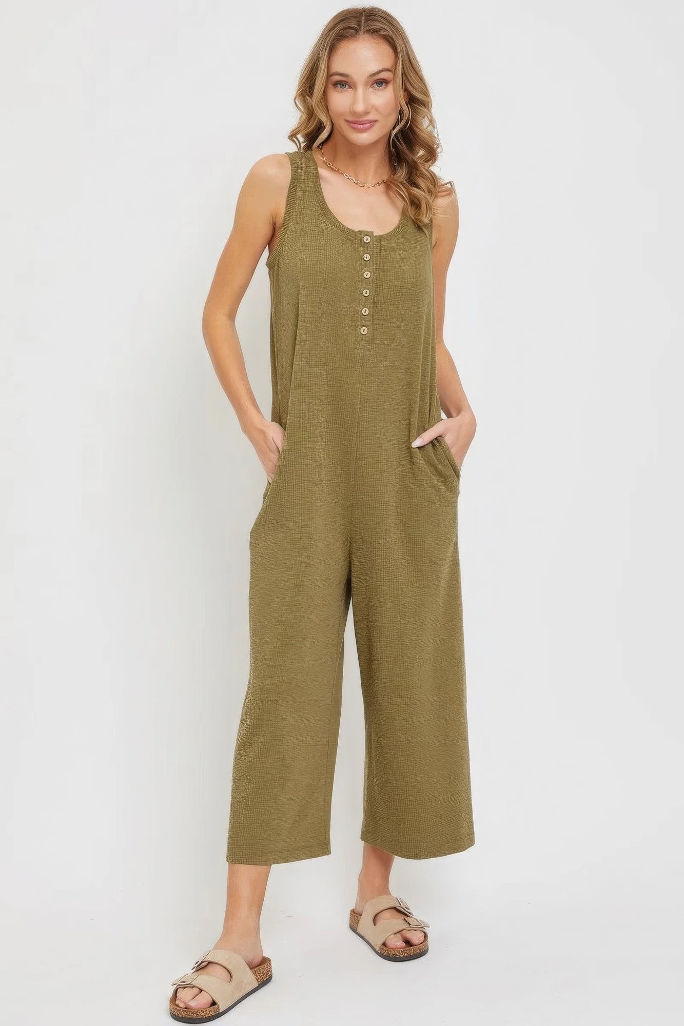 Chic women's casual buttondown jumpsuit in green with side pockets, sleeveless design, and button-up front, made from soft jersey knit.