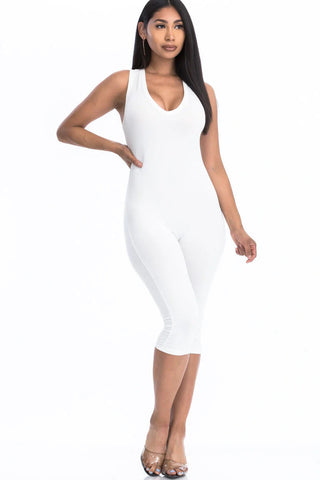 Woman wearing a chic white capri jumpsuit with racer back, showcasing a slenderizing silhouette and trendy summer style.