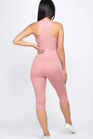 Woman wearing pink sleeveless racer back capri jumpsuit in soft jersey fabric, showcasing a slenderizing silhouette and comfortable fit.