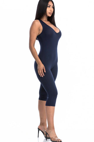Woman wearing navy sleeveless racer back capri jumpsuit, highlighting high-stretch fabric and slenderizing silhouette.