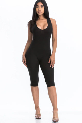 Woman wearing a black racer back capri jumpsuit with a sleeveless design, showcasing a chic summer fashion trend.