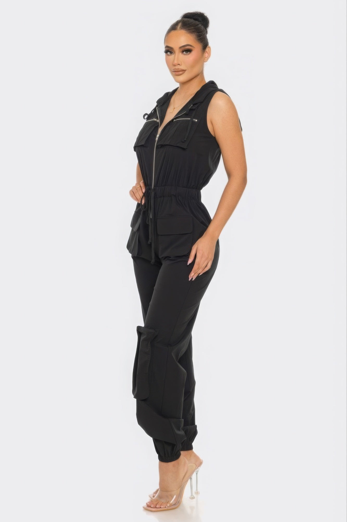 Elegant woman modeling black Chic Women's Tracy Cargo Jumpsuit with utility design and hoodie, showcasing fashionable one-piece ensemble.