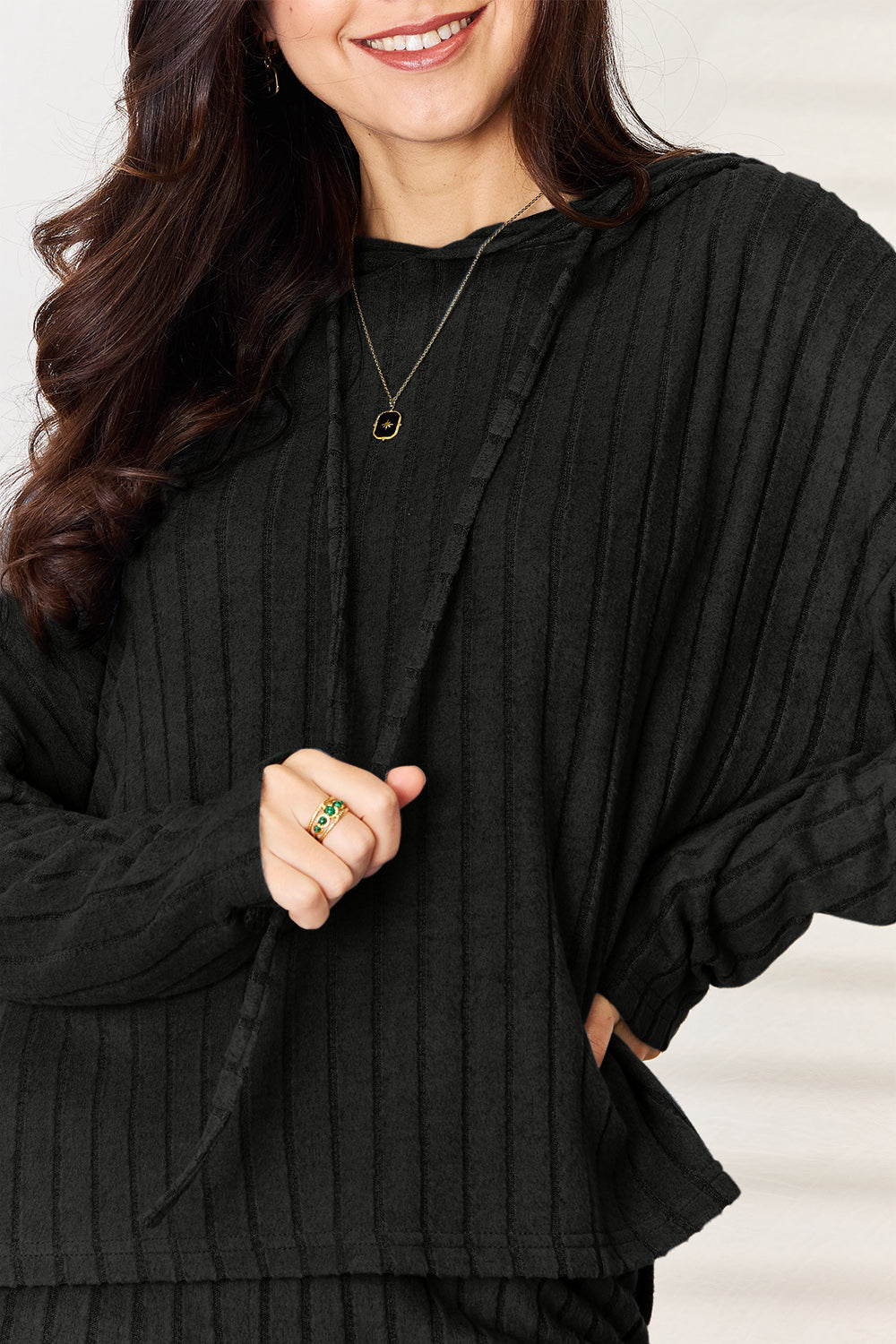 Woman wearing a ribbed, black Chill Day Hooded Top from two-piece set, featuring drawstrings and slight stretch for comfort.