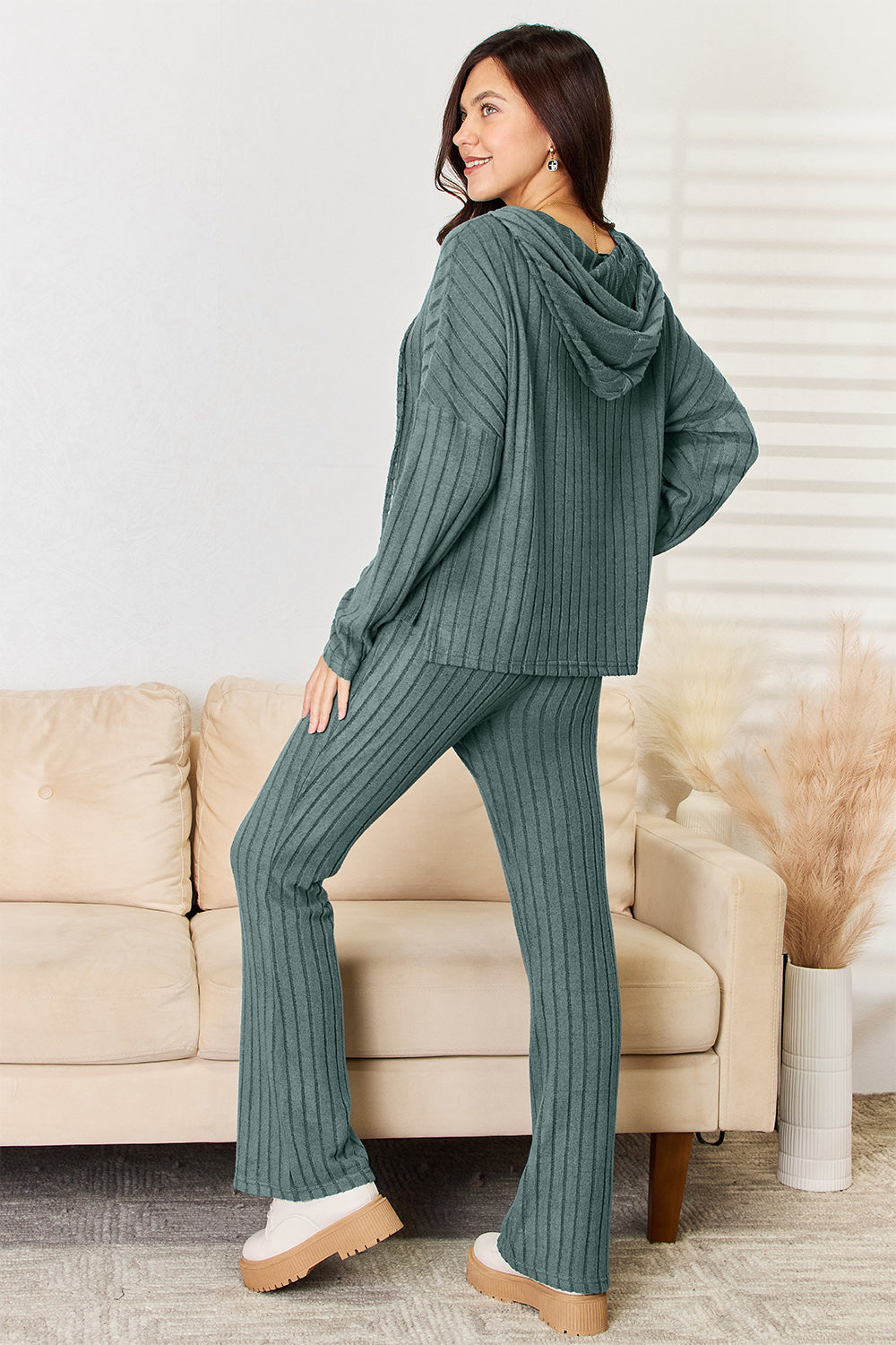 Woman wearing a green ribbed Chill Day Hooded Top and Straight Pants Set with drawstring, slightly stretchy fabric, in a cozy setting.