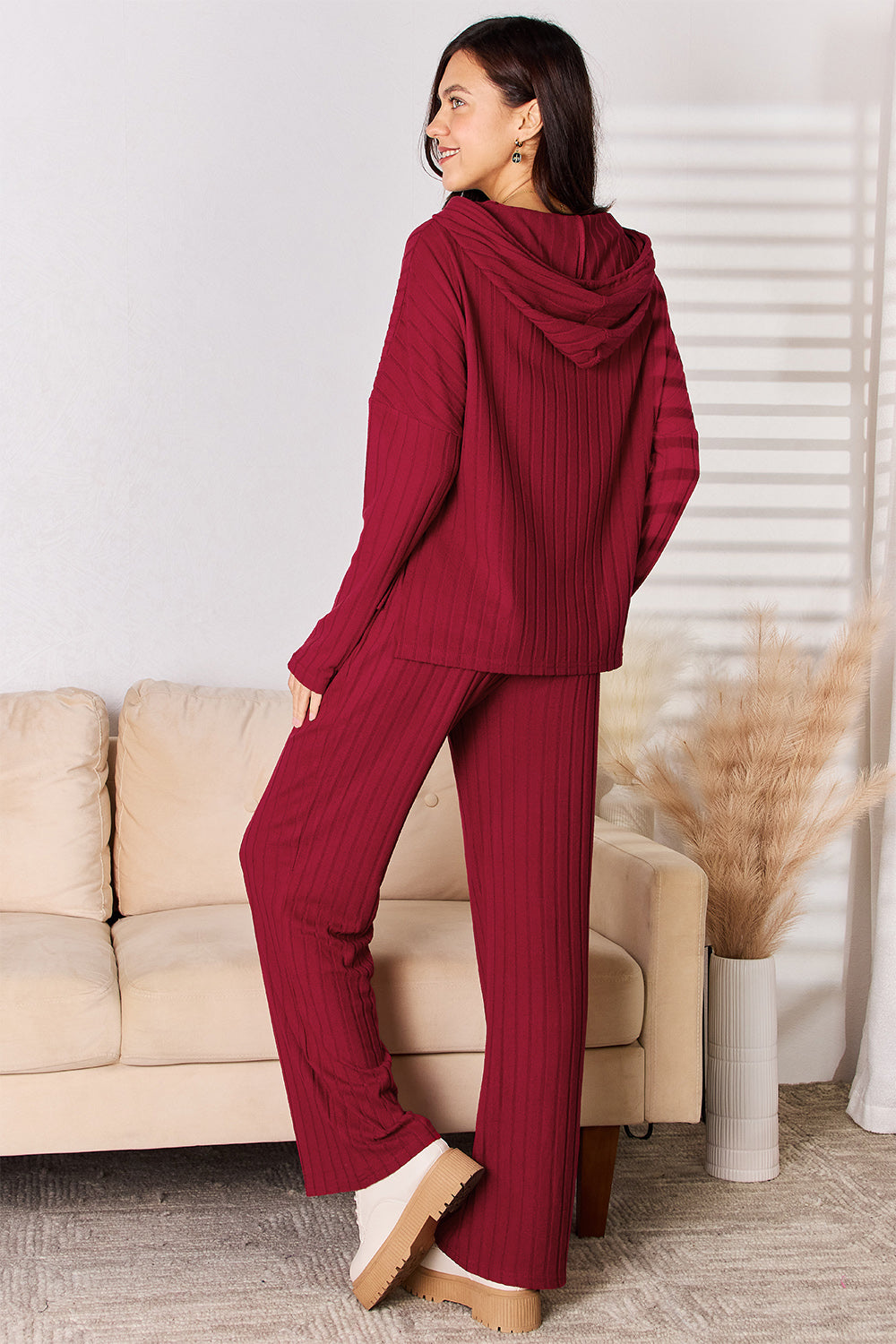 Woman wearing a red Chill Day Hooded Top and Straight Pants Set, featuring drawstring and ribbed design, in a cozy living room setting.