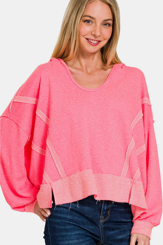 Woman wearing pink contrast trim slit hoodie with raw hem.