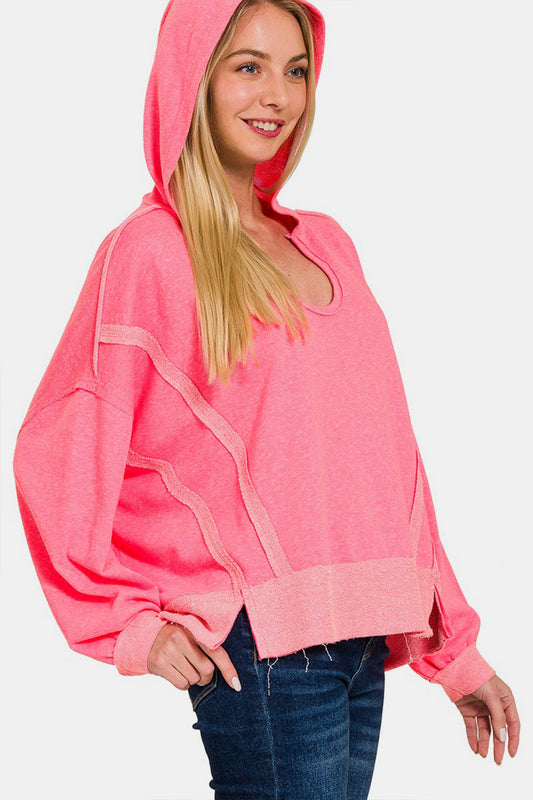 Woman wearing a pink contrast trim slit hoodie with raw hem and no stretch fabric, featuring polyester, cotton, and rayon blend.