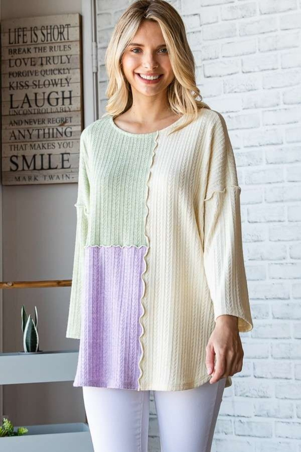 Woman wearing a color block round neck dropped shoulder blouse in light pastel shades, featuring a slightly stretchy material.