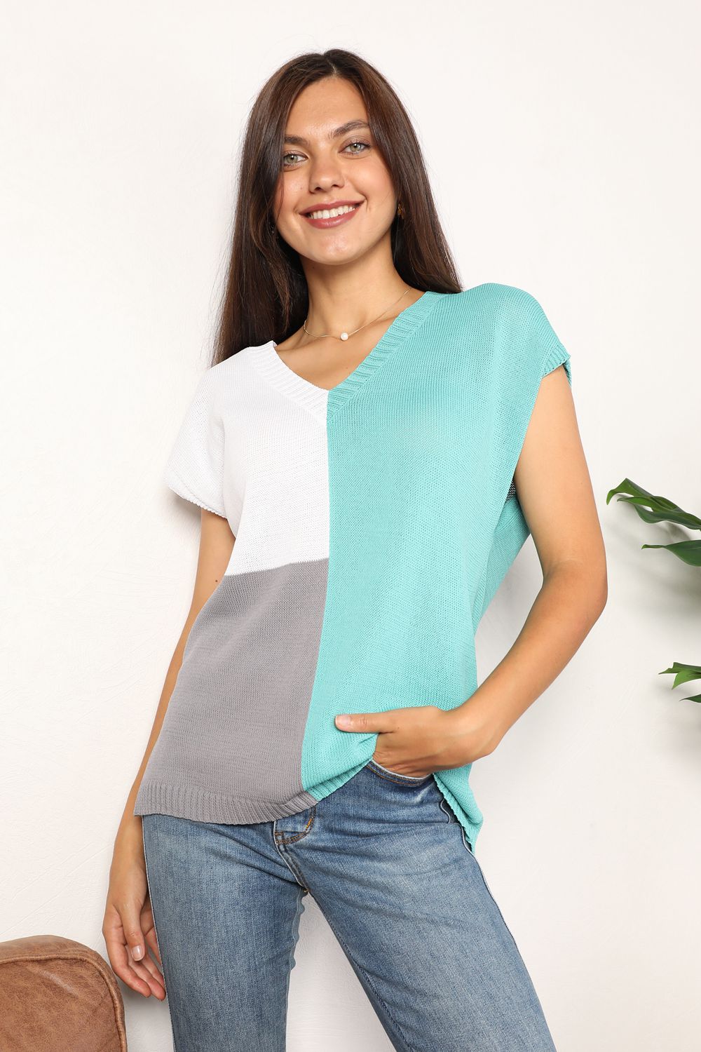 Woman wearing color block V-neck knit top with short sleeves, showcasing a stylish and relaxed look, paired with jeans.