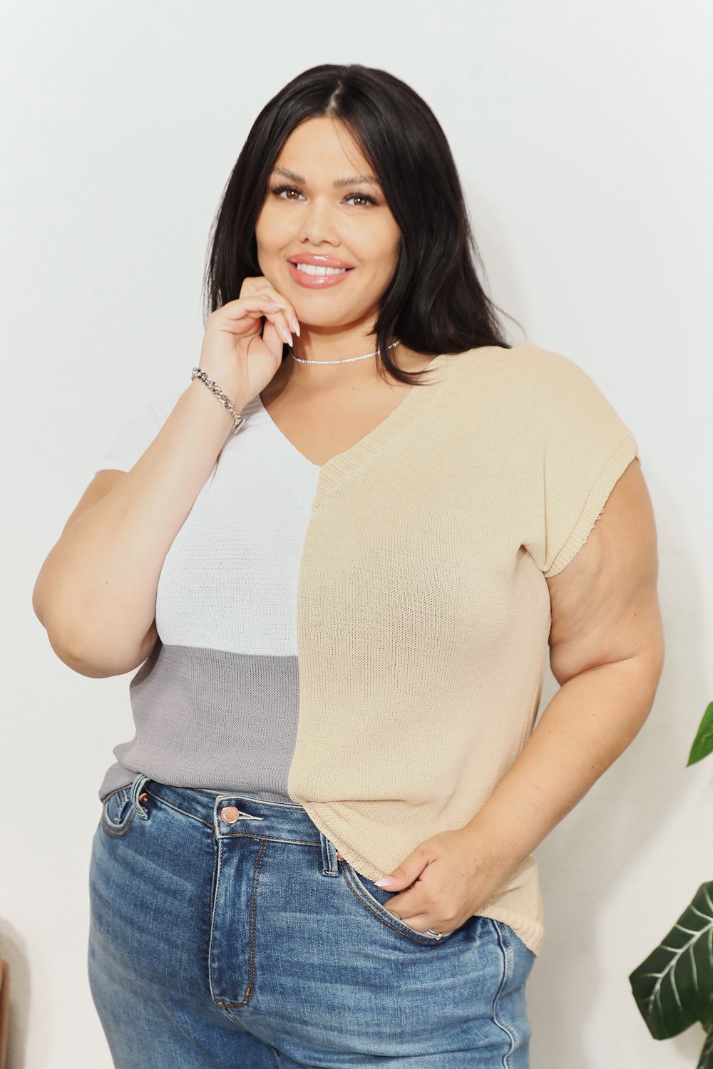 Woman wearing color block V-neck knit top with short sleeves and jeans, showcasing a chic, comfortable style.