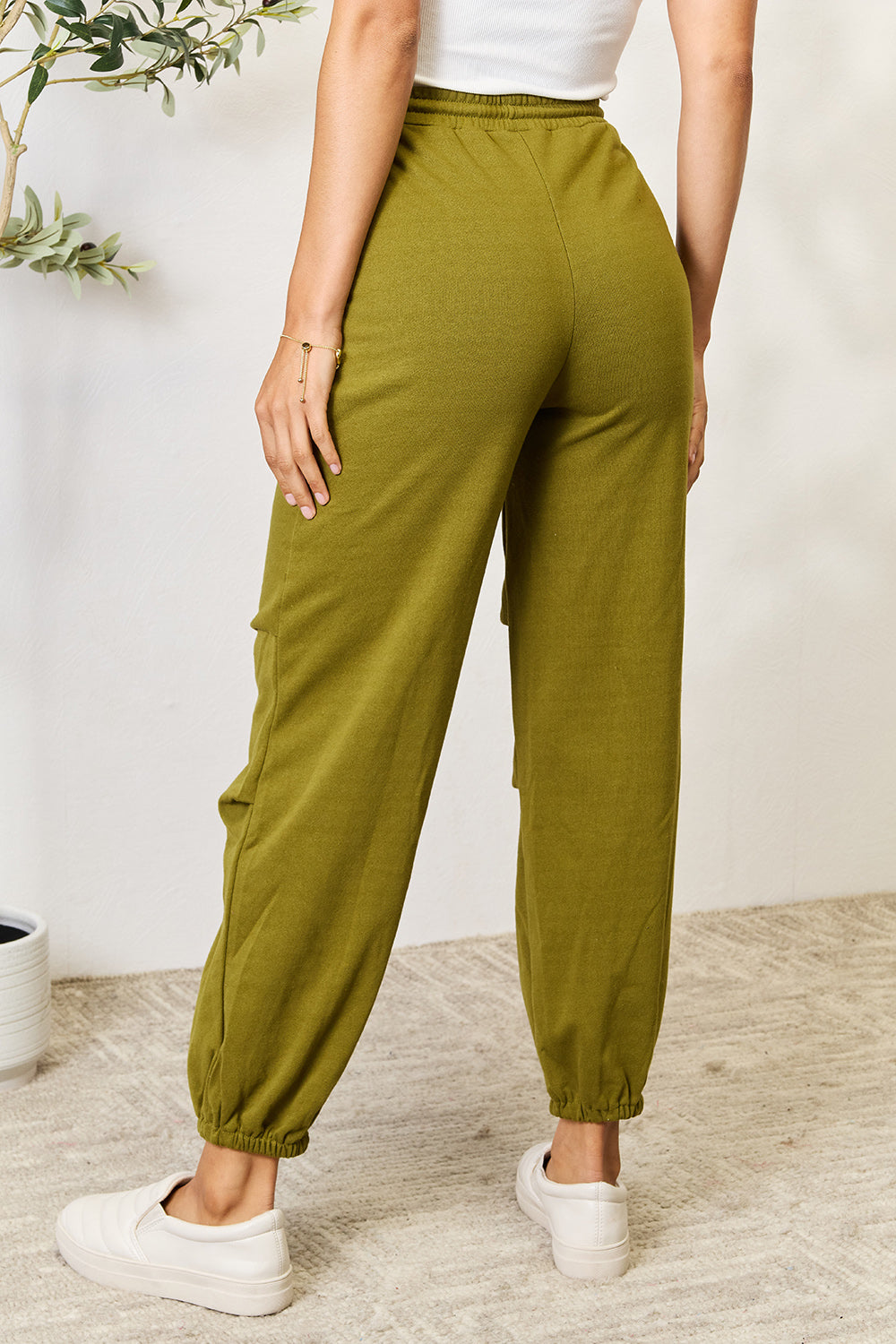 Olive green drawstring sweatpants with pockets, made of cotton and polyester, featuring a basic style and opaque fabric.