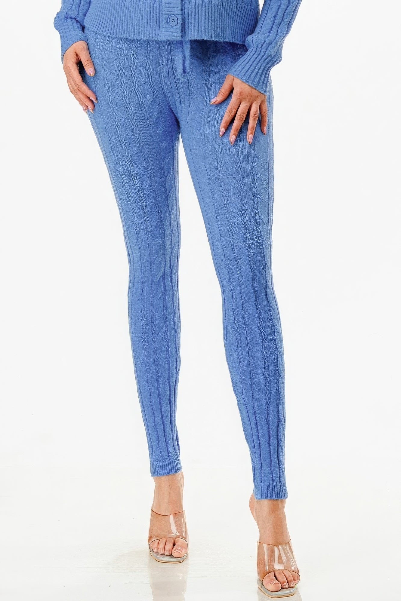 Woman wearing blue cable knit sweater and pants set with nude heels.