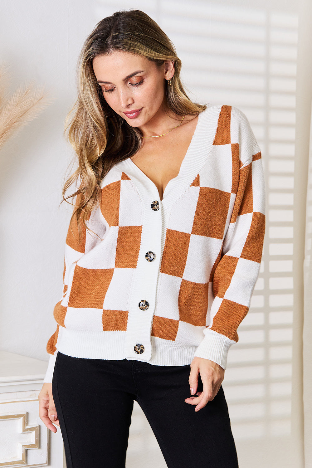 Woman wearing checkered button-up V-neck cardigan with dropped shoulders and relaxed fit.