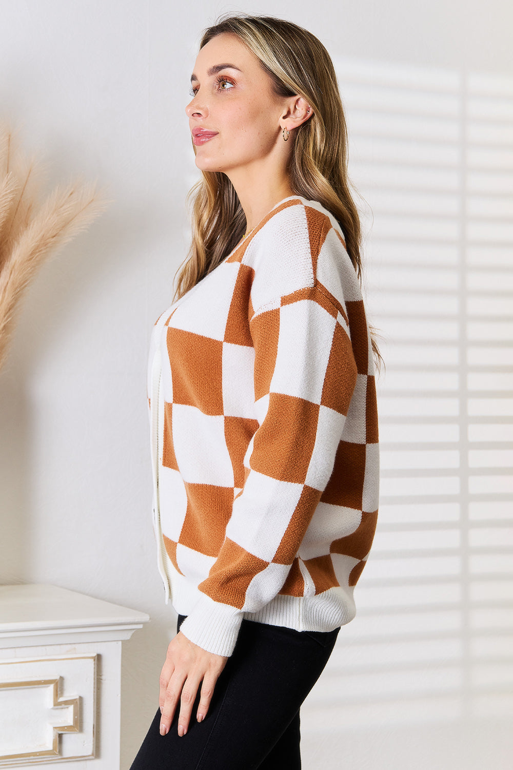 Woman wearing checkered button-up V-neck cardigan, showcasing relaxed dropped shoulder fit and versatile design.