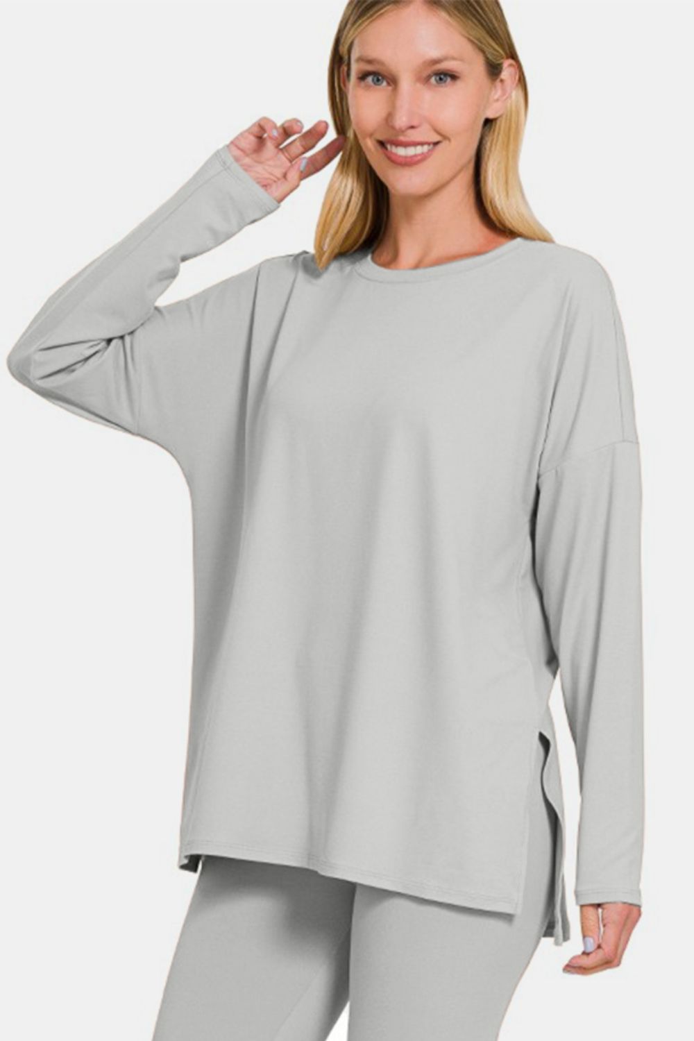 Woman in a gray brushed microfiber lounge set with slit, featuring a comfortable top and leggings made of high-stretch polyester-spandex blend.