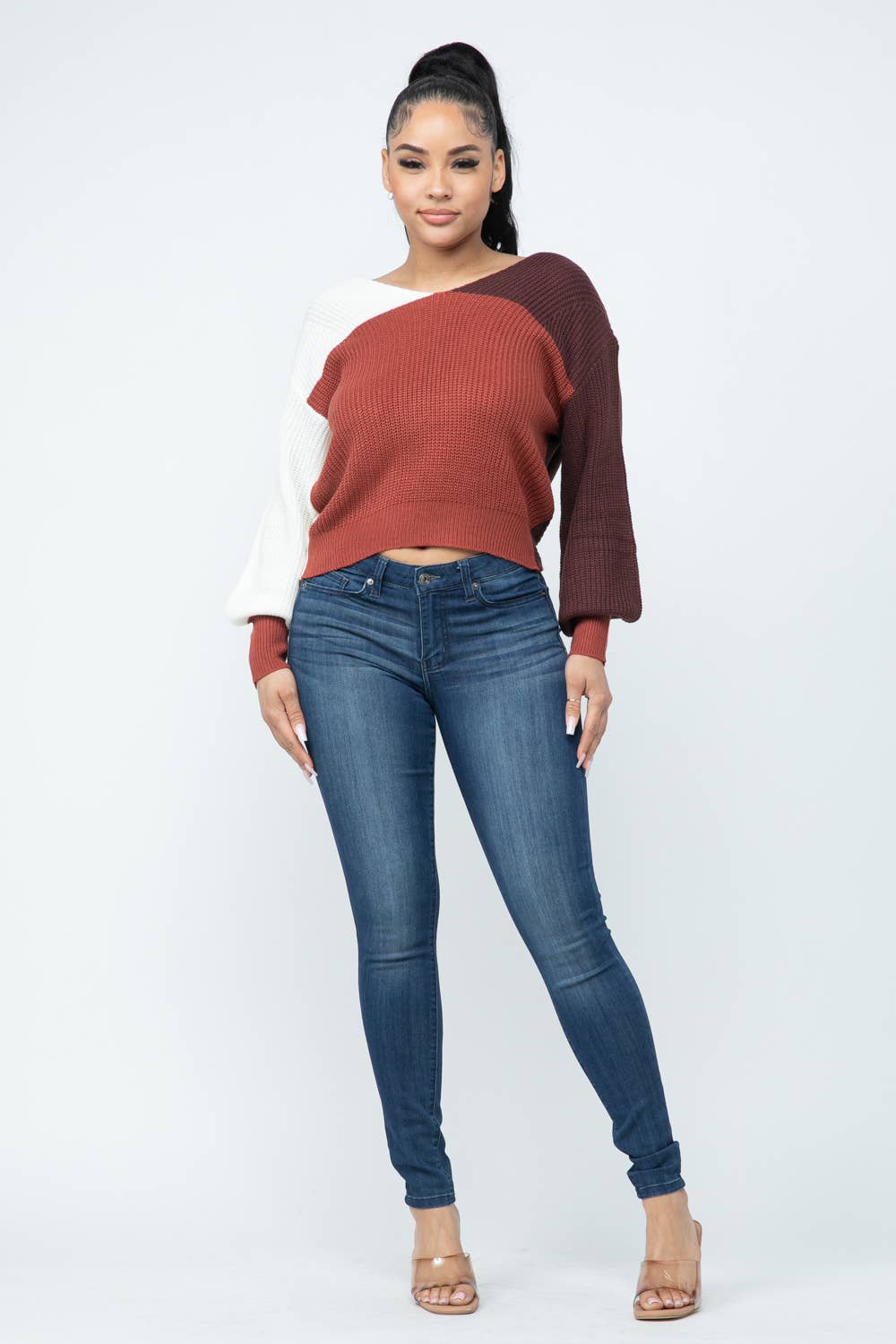 Woman wearing color block twisted open back cozy sweater with jeans, showcasing a stylish and comfortable loose fit design.