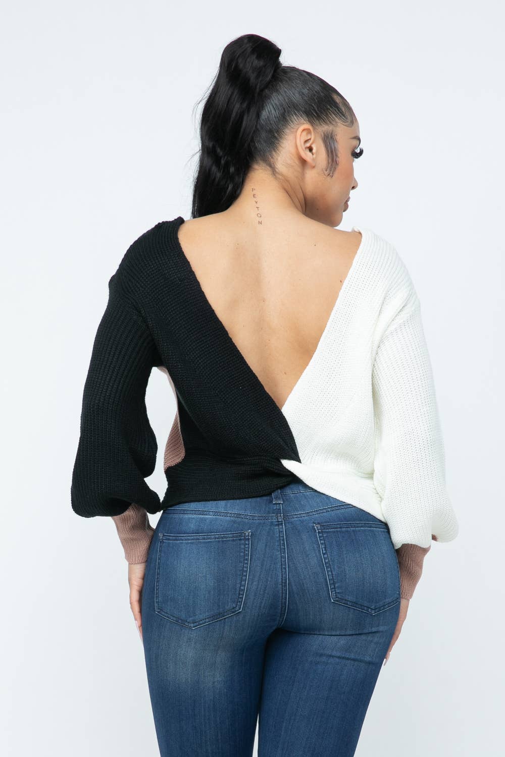 Color block sweater with twisted open back and loose fit, showcasing cozy style. Ideal for casual wear. Model shown from the back.