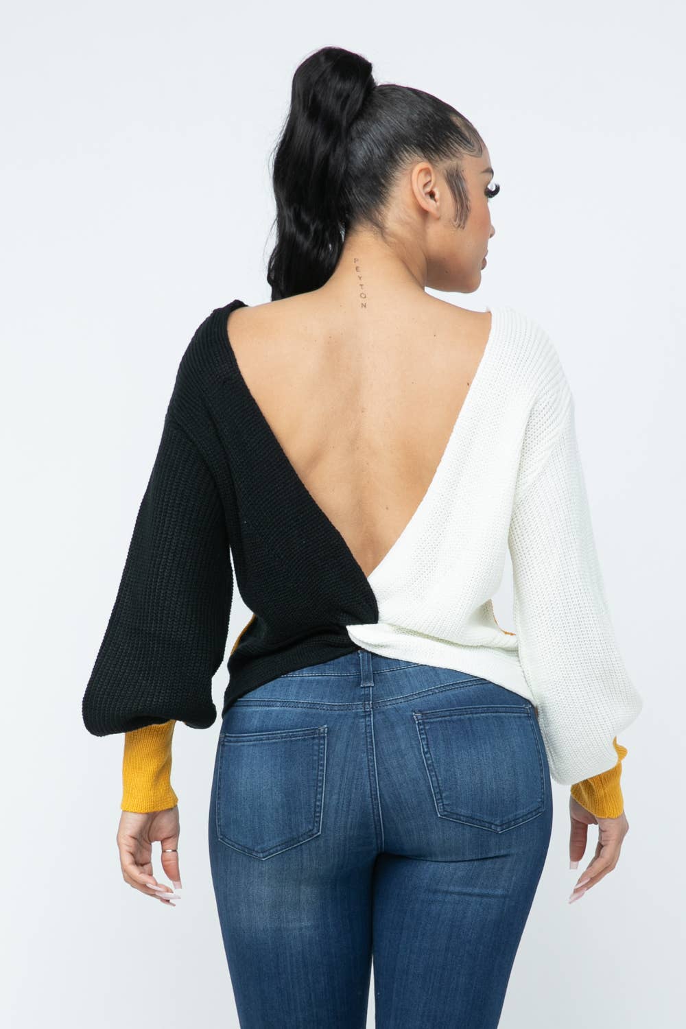 Cozy color block sweater with twisted open back, loose fit, and contrasting black and white design. Perfect for stylish, comfortable wear.