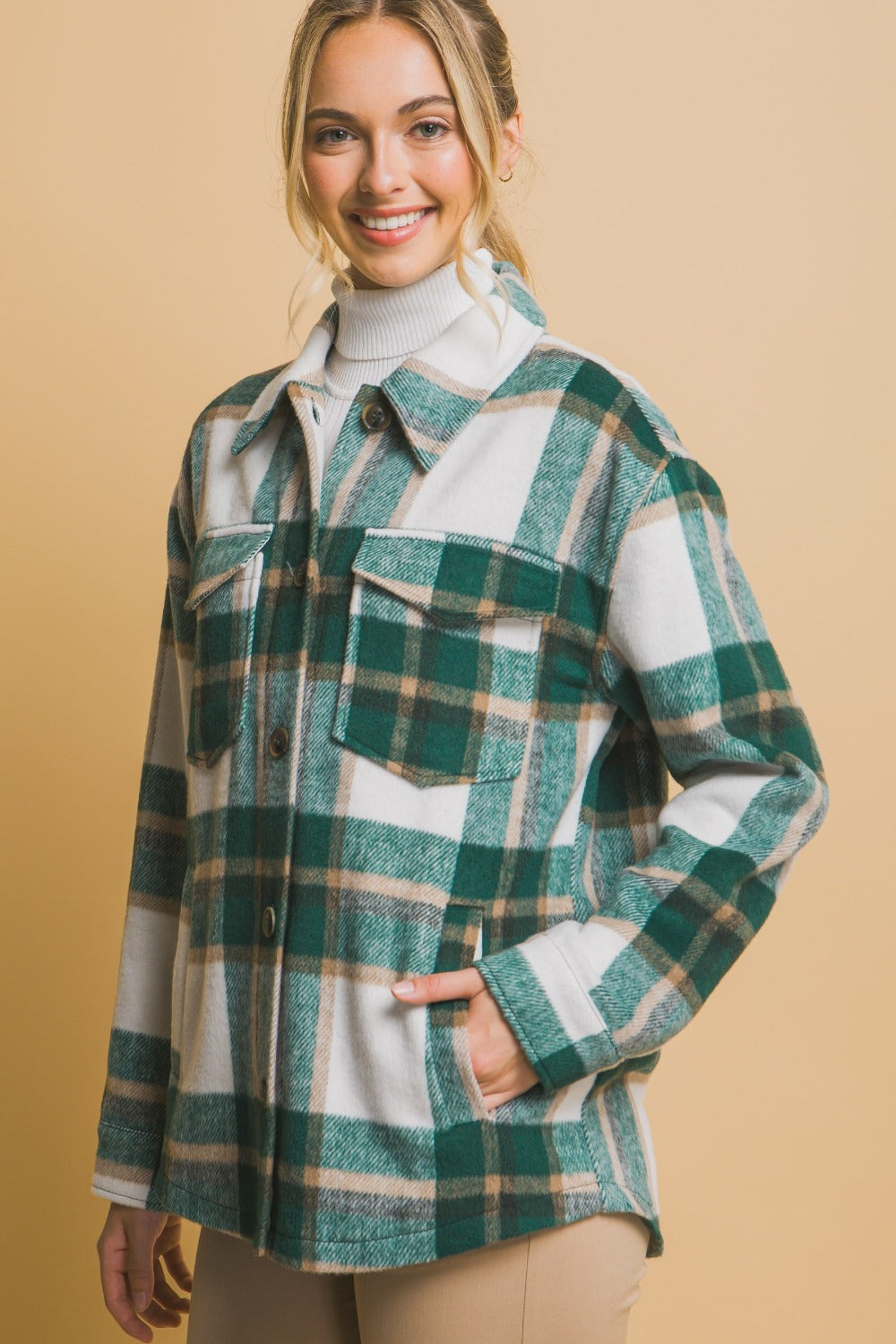 Woman wearing green plaid button-up shacket with pockets, made of 100% polyester.