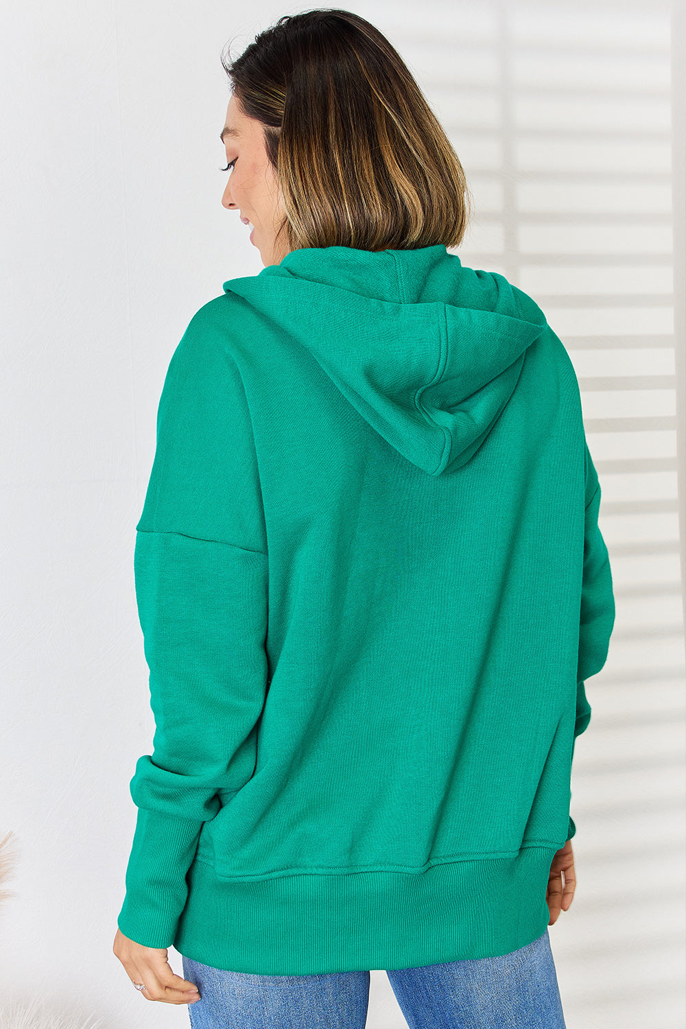 Woman wearing green half snap long sleeve hoodie made of 60% cotton and 40% polyester, showcasing basic style with no stretch.