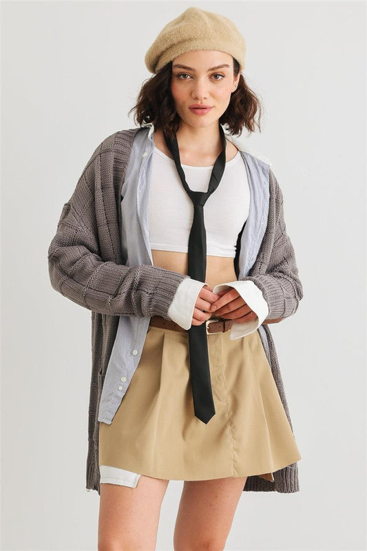 Woman wearing knit two pocket long sleeve cardigan with open front, tied tie, beige skirt, and beret.