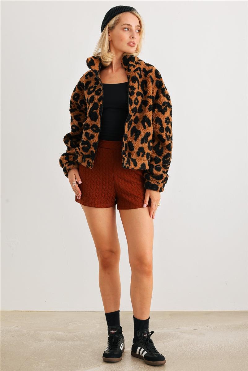 Woman wearing fuzzy leopard print teddy jacket with turtle neckline, front zip, and two pockets, paired with shorts and sneakers.