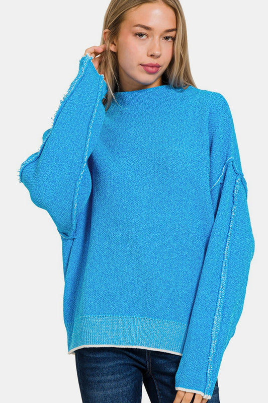 Woman wearing a blue cozy exposed seam mock neck long sleeve sweater made of 79% polyester and 21% acrylic.