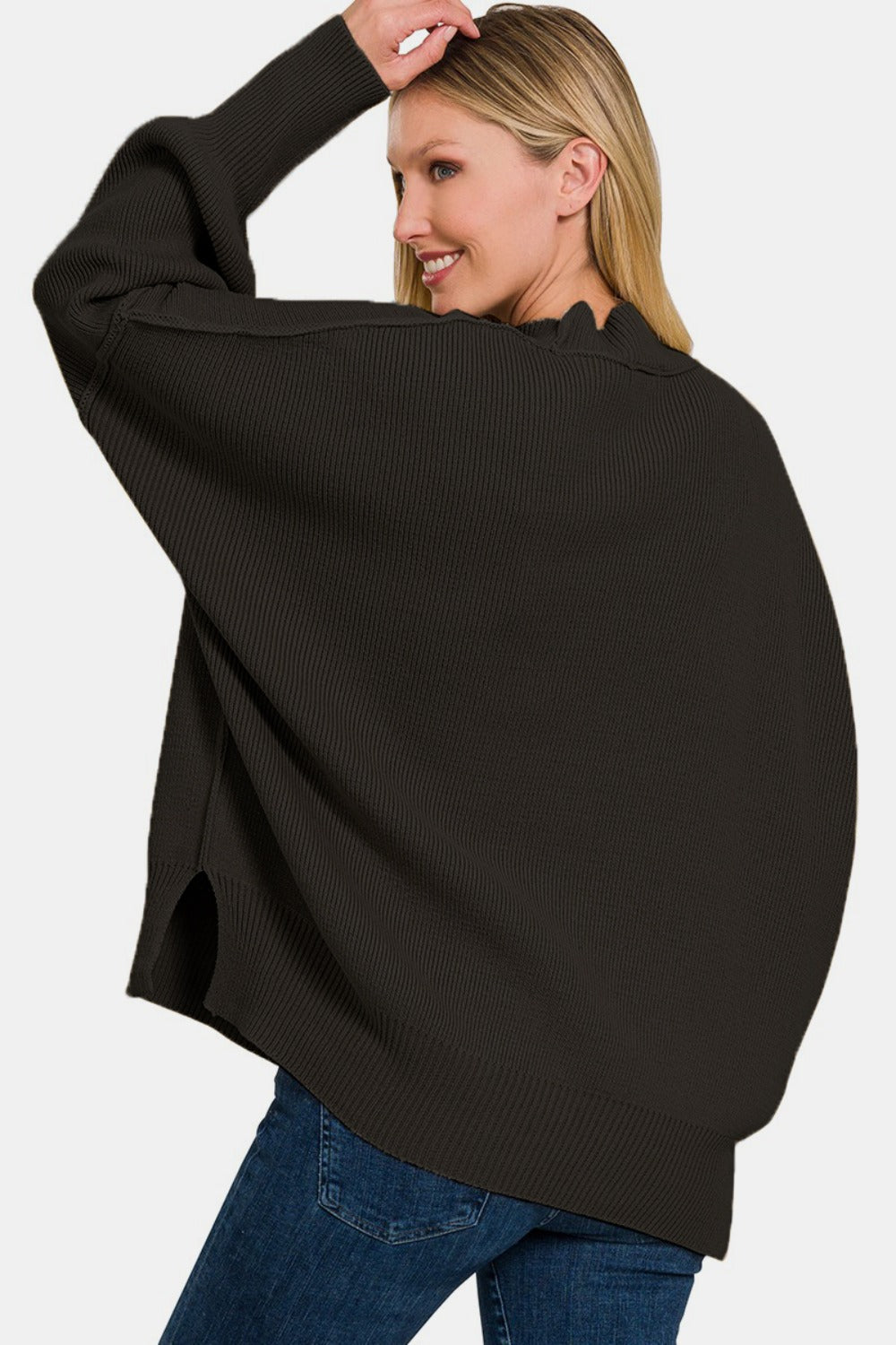 Woman wearing a cozy black oversized sweater with trendy exposed seams and side slits, perfect for casual outings.