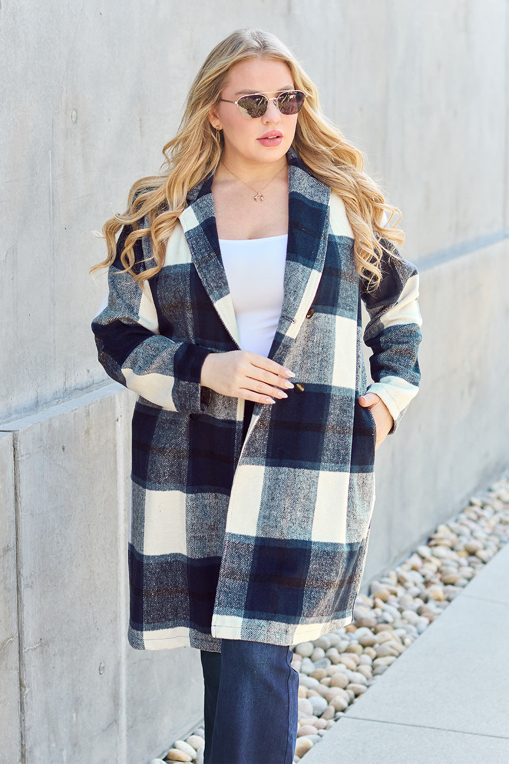 Woman wearing full size plaid button up lapel collar coat with pocketed design made of 100% polyester, standing outdoors.