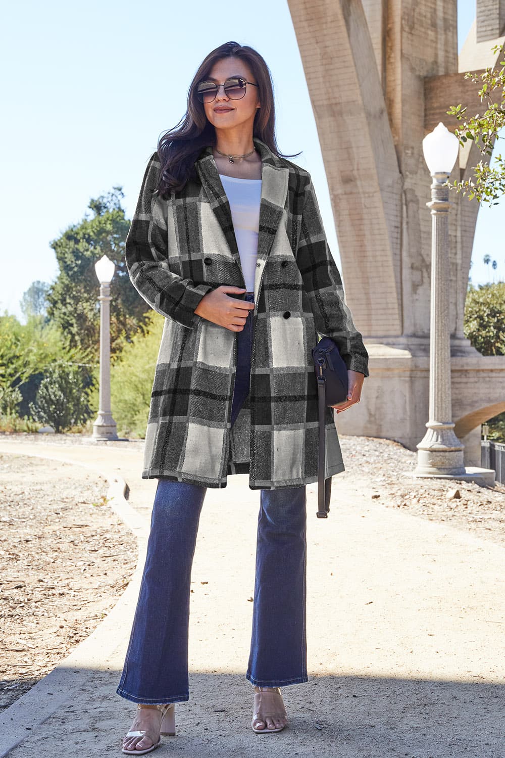 Stylish woman wearing a full-size plaid button-up lapel collar coat with pockets, made of 100% polyester, outdoors.