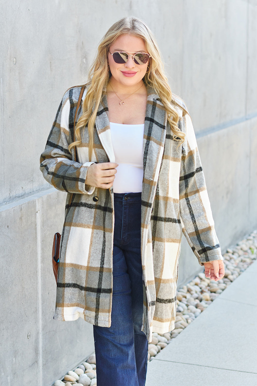 Woman wearing a full-size plaid button-up lapel collar coat with pockets, made of 100% polyester, walking outdoors.