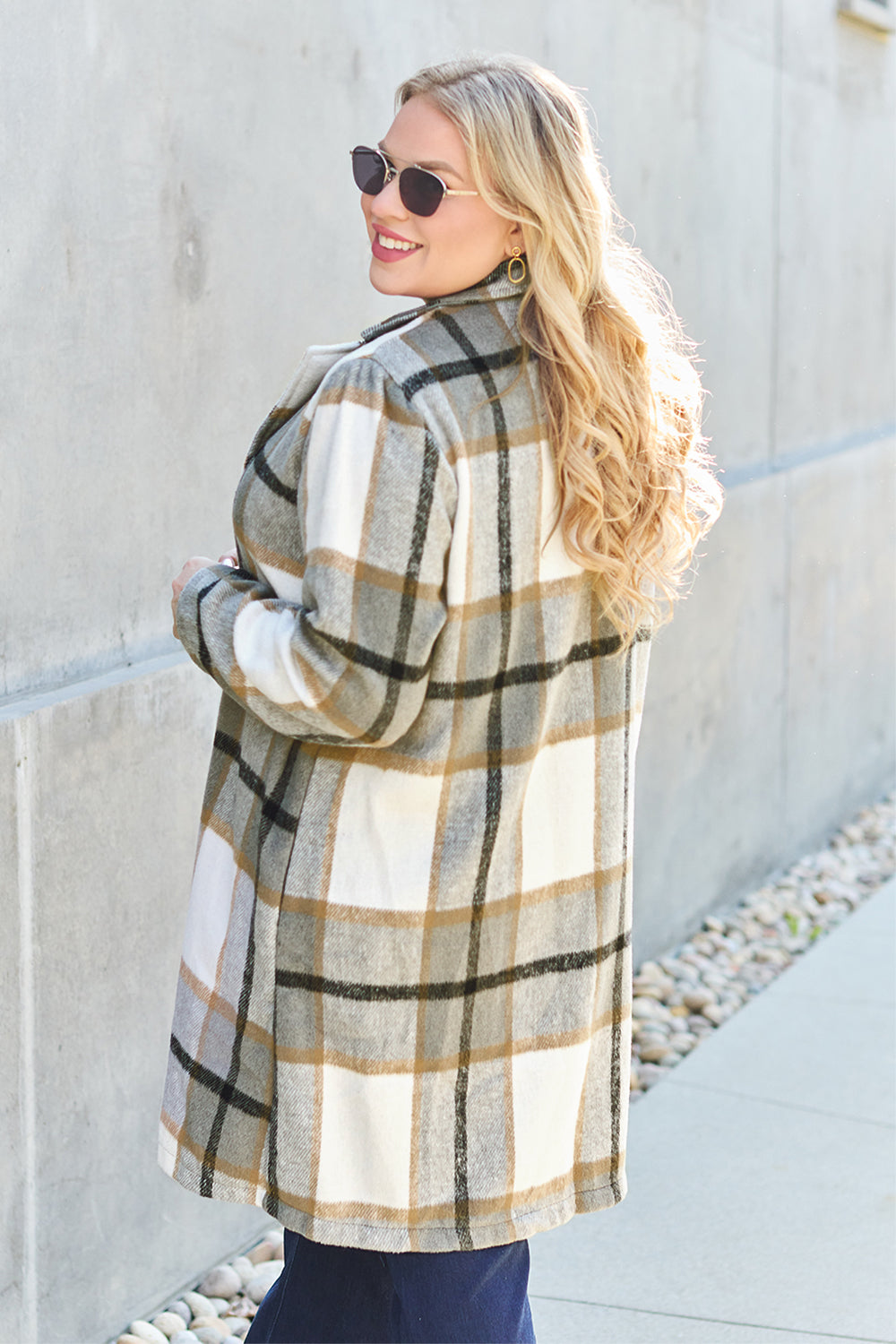 Woman wearing a full-size plaid button-up lapel collar coat with pocket, made of 100% polyester, standing outdoors.